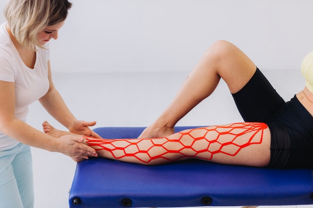 Кинезио ростов на дону фото медицинский Premium Photo Female doctor helps woman by putting kinesio tape on her leg. youn