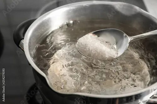Кипящая вода фото Salting boiling water in pot on stove, closeup фотография Stock Adobe Stock