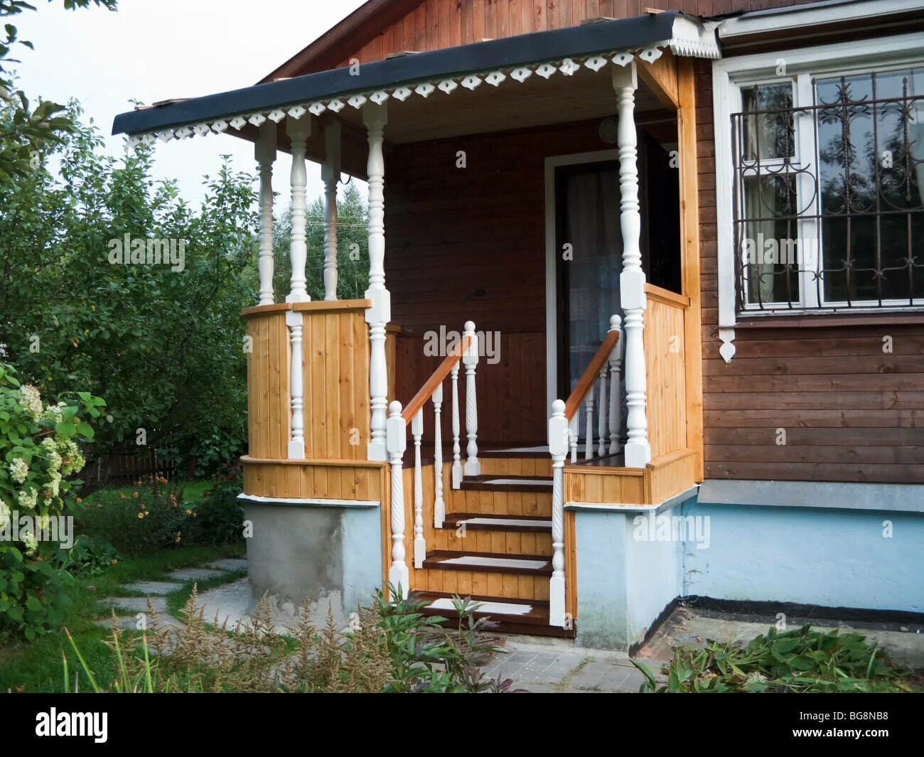 Крыльцо в деревенском доме варианты The pictures shows a new wooden porch in a country house, surrounded by green tr