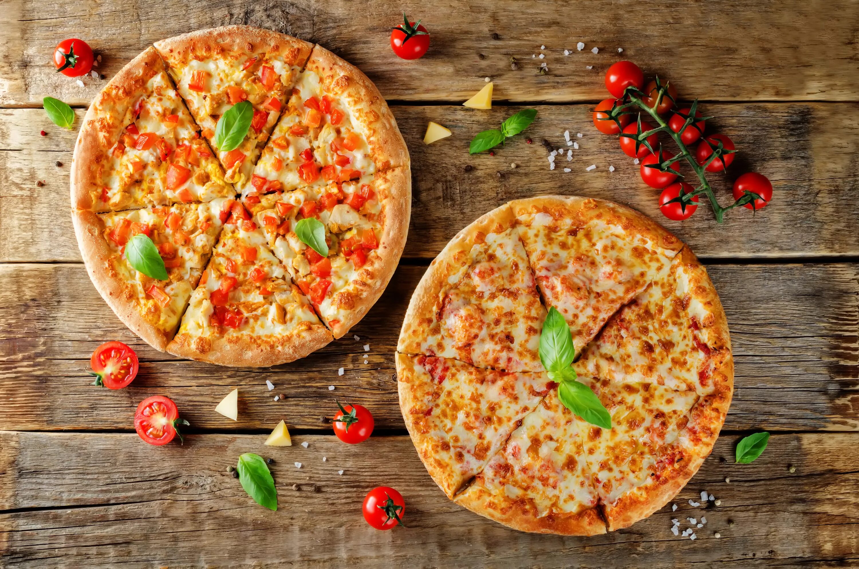Пицца фото сверху Two pizzas with cheese and bell peppers on a table with tomatoes Desktop wallpap