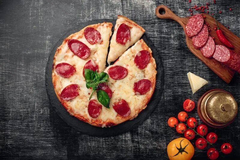 Пицца на тарелке фото Pizza with Cheese and Salami on a Stone and a Black Chalk Board Stock Image - Im