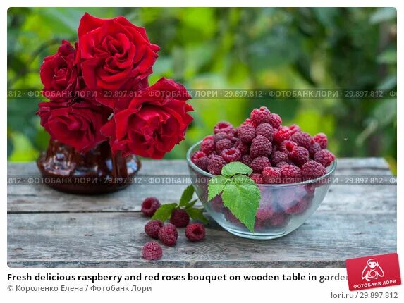 Подписать фото с малиной Fresh delicious raspberry and red roses bouquet on wooden table in garden. Стоко