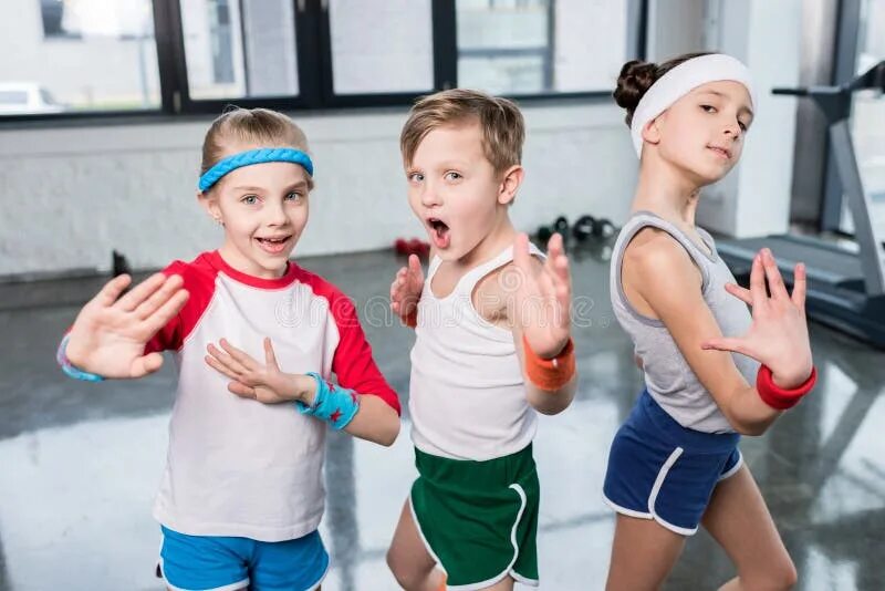 Подписать фото спорт ребенок Group of Little Kids in Sportswear Exercising and Posing at Camera in Gym Stock 