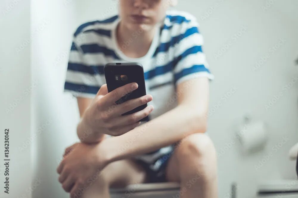 Подростки в туалете фото Teenager with a smartphone on toilet фотография Stock Adobe Stock