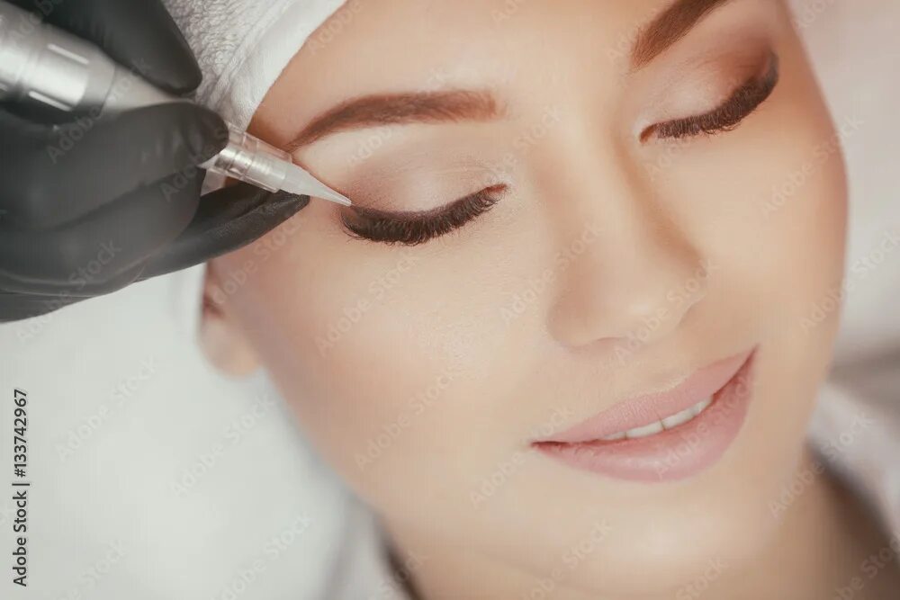 Показать фото перманентного макияжа Cosmetologist making permanent make up at beauty salon Фотографія Stock Adobe St