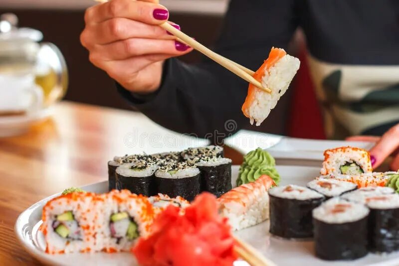 Показать роллы и суши фото Sushi and Rolls, Japanese Cuisine, a Girl Eating Sushi Stock Photo - Image of go