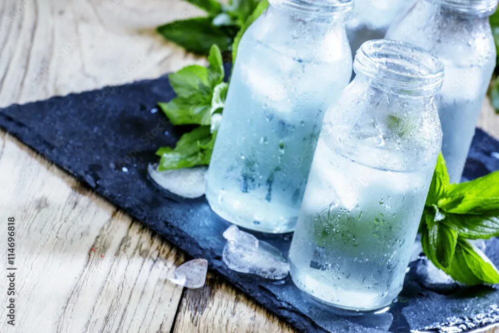 Полезная вода фото Very cold mineral water with ice in a misted glass bottles, dark Фотографія Stoc