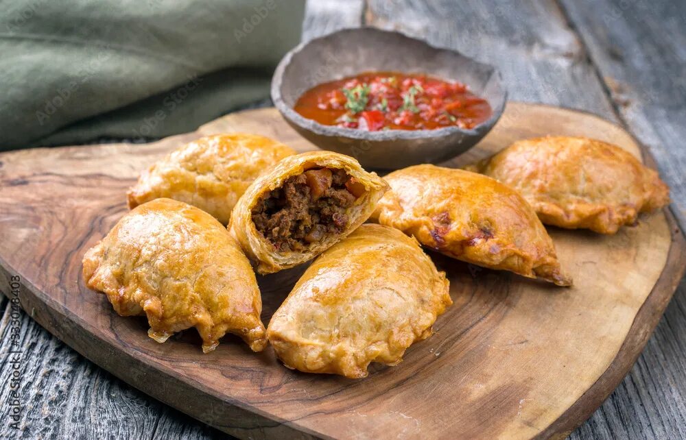 Посикунчики что это за блюдо фото Traditional South American empanada de carne offered with a chili dip as closeup