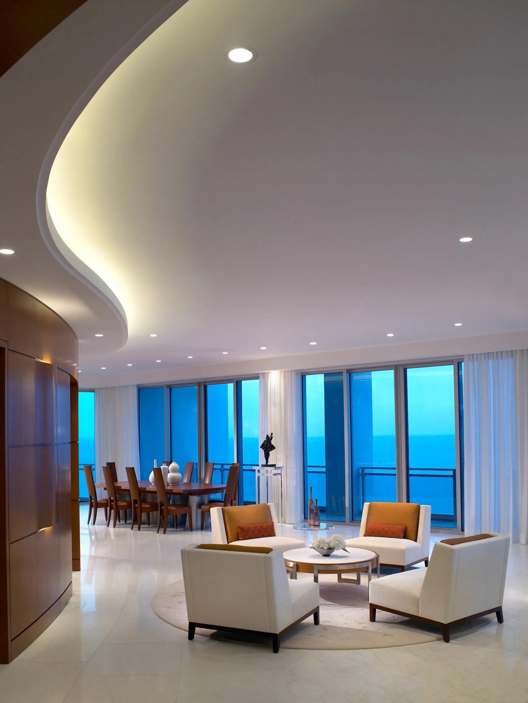 Потолок навесной натяжной фото A curved ceiling and wood feature wall complement the ocean waves in the lounge.