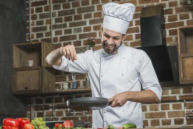 Повар с мясом фото Souriant Chef Debout Dans La Cuisine, Saupoudrer Des épices Sur La Poêle à Frire