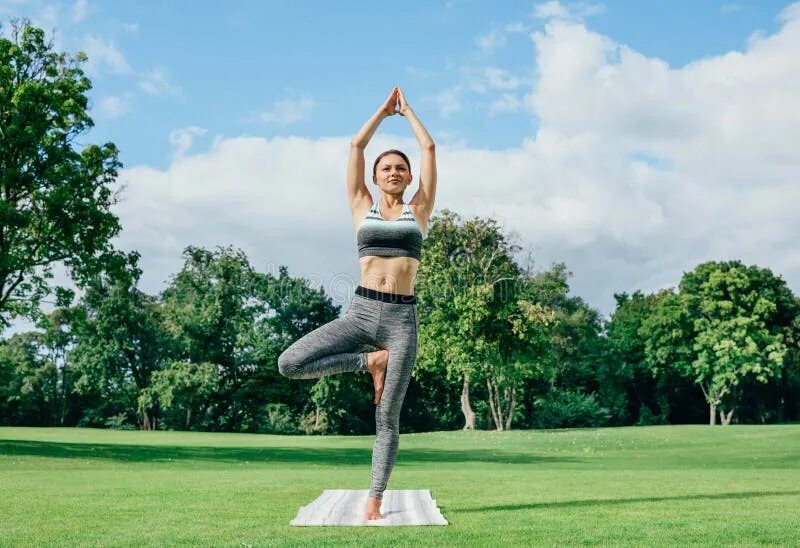 Поза дерева в йоге фото Woman meditating in park stock photo. Image of sportive - 99436950