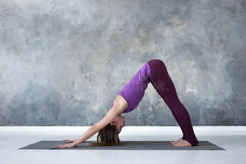 Поза собаки в йоге фото Woman Doing Yoga Exercise Downward Facing Dog Pose or Adho Mukha Svanasana. Stoc