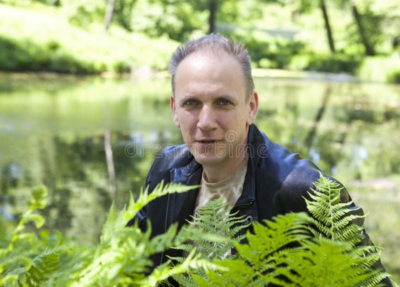 Прическа озеро Summer Portrait of the Mature Man through Fern Leaves on a Background of the For