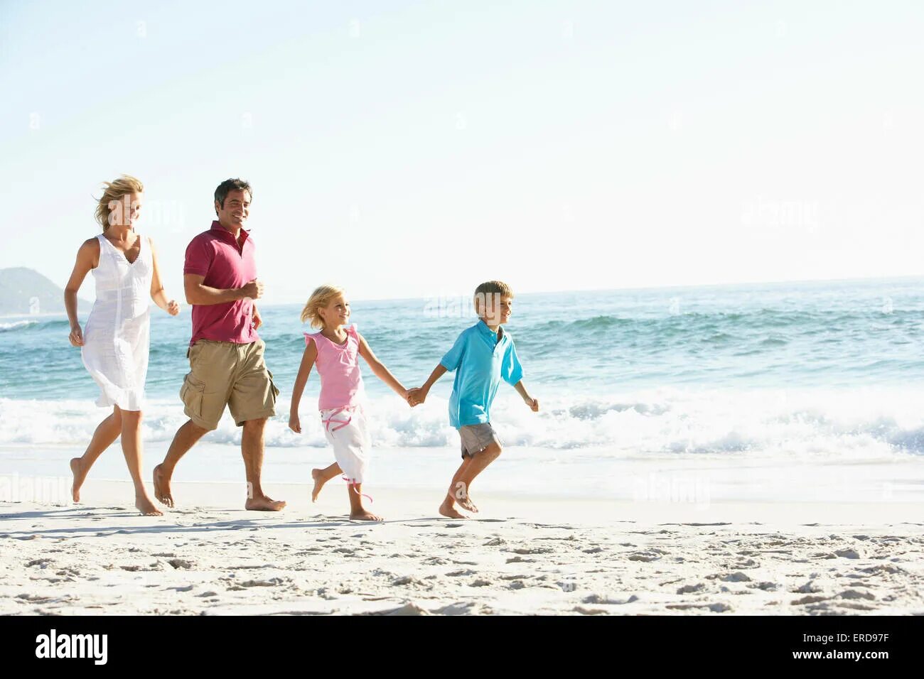 Про здоровье семейная ул 3 фото Young Family Running Along Sandy Beach On Holiday Stock Photo - Alamy