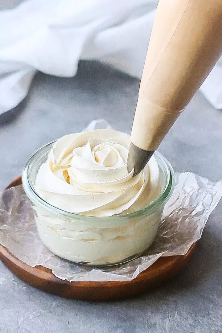 Простой крем для торта с фото Swiss meringue buttercream being piped into a shallow glass dish, on a wood plat