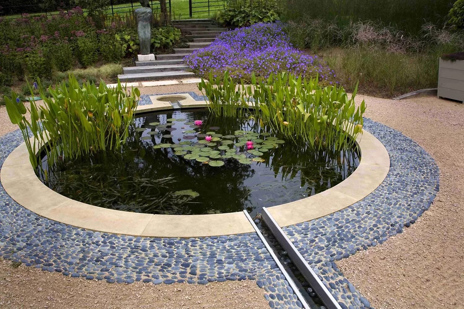 Пруд на участке дизайн фото Circular pond with clean lines, surrounded by blue-ish river rock and pea gravel