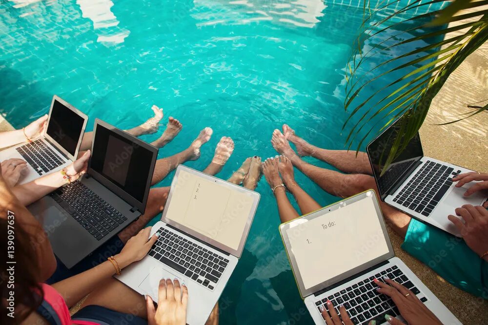 Работа летом фото Group of people freelancers using laptop computer sitting near swimming pool and