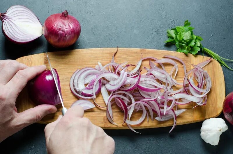 Рассорка на лук фото A Man Cuts Red Onions on a Wooden Chopping Board with a Kitchen Knife. Hands Clo