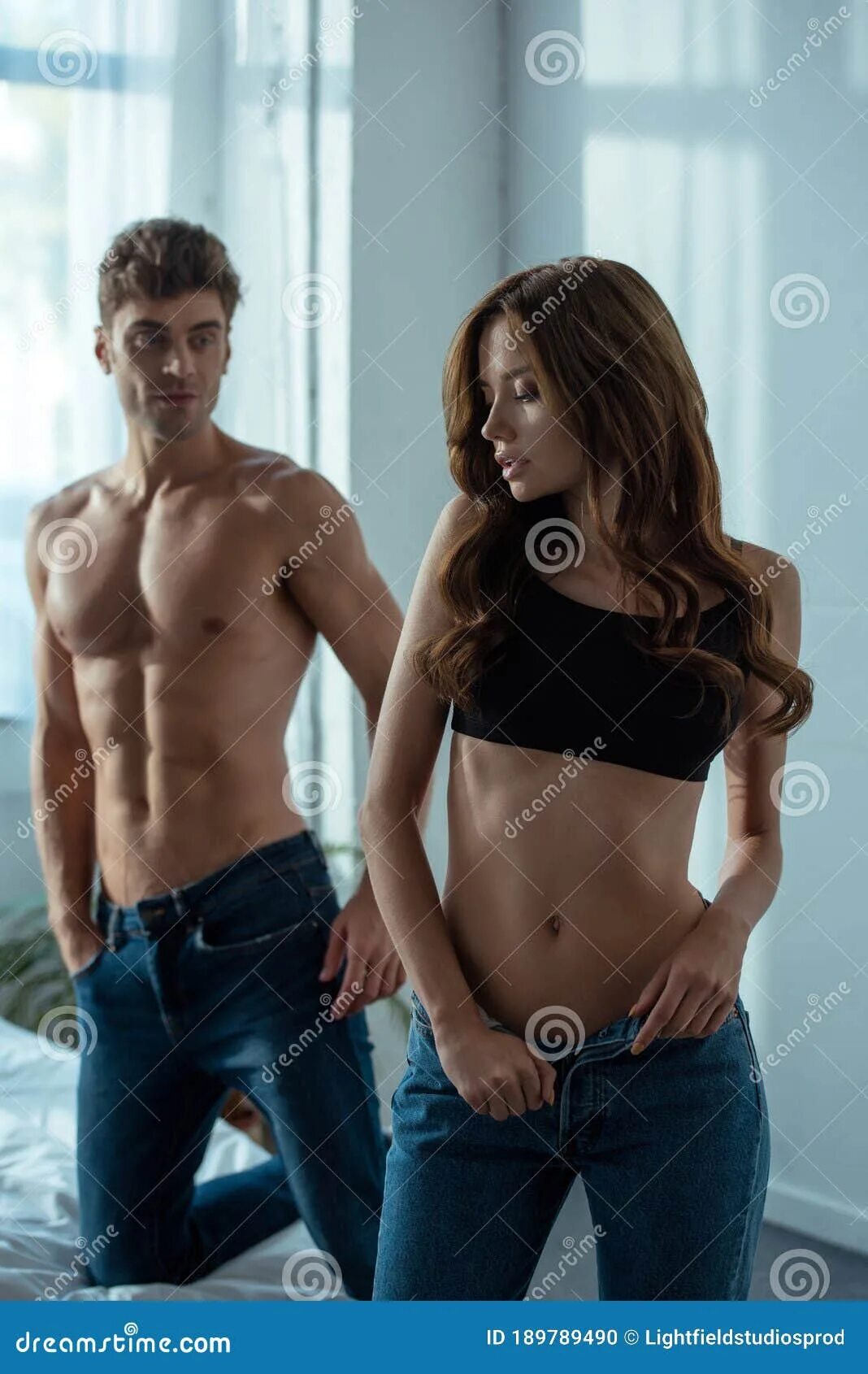 Раздеть девушку по фото лучшие Focus of Attractive Girl Undressing in Bedroom Near Handsome Man Stock Photo - I