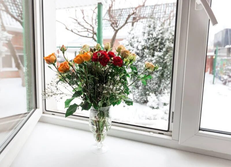 Реальное фото цветов на окне A Bouquet of Roses in a Glass Vase Stand on a Wooden Stool Against the Backgroun