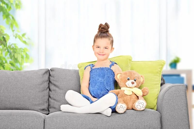 Ребенок на диване фото Cute Little Girl Sitting with Teddy Bear on a Sofa Stock Image - Image of couch,