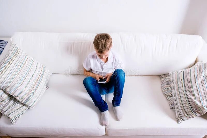 Ребенок на диване фото Children at Home Sitting on Sofa, Playing with Laptop Stock Image - Image of con