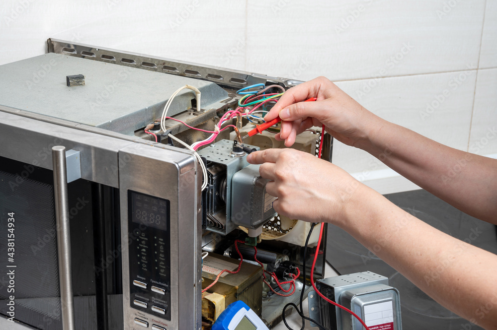 Ремонт микроволновых своими Repair of the microwave oven. A woman measures the electrical characteristics wi